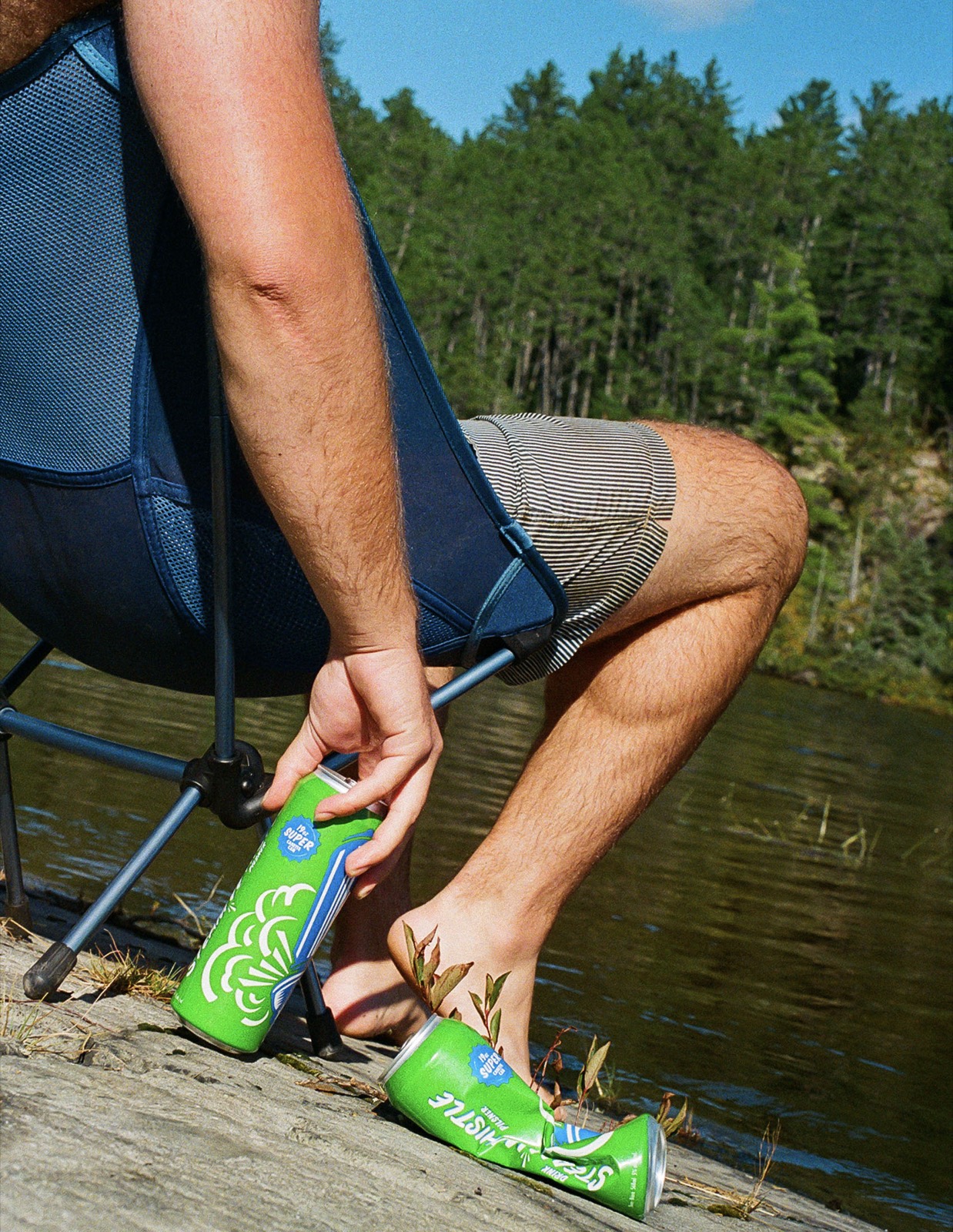 Person on a lakeside chair opening a Steam Whistle can in Temagami