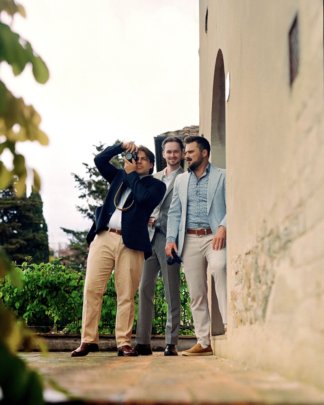 Group of friends laughing on a park bench with drinks
