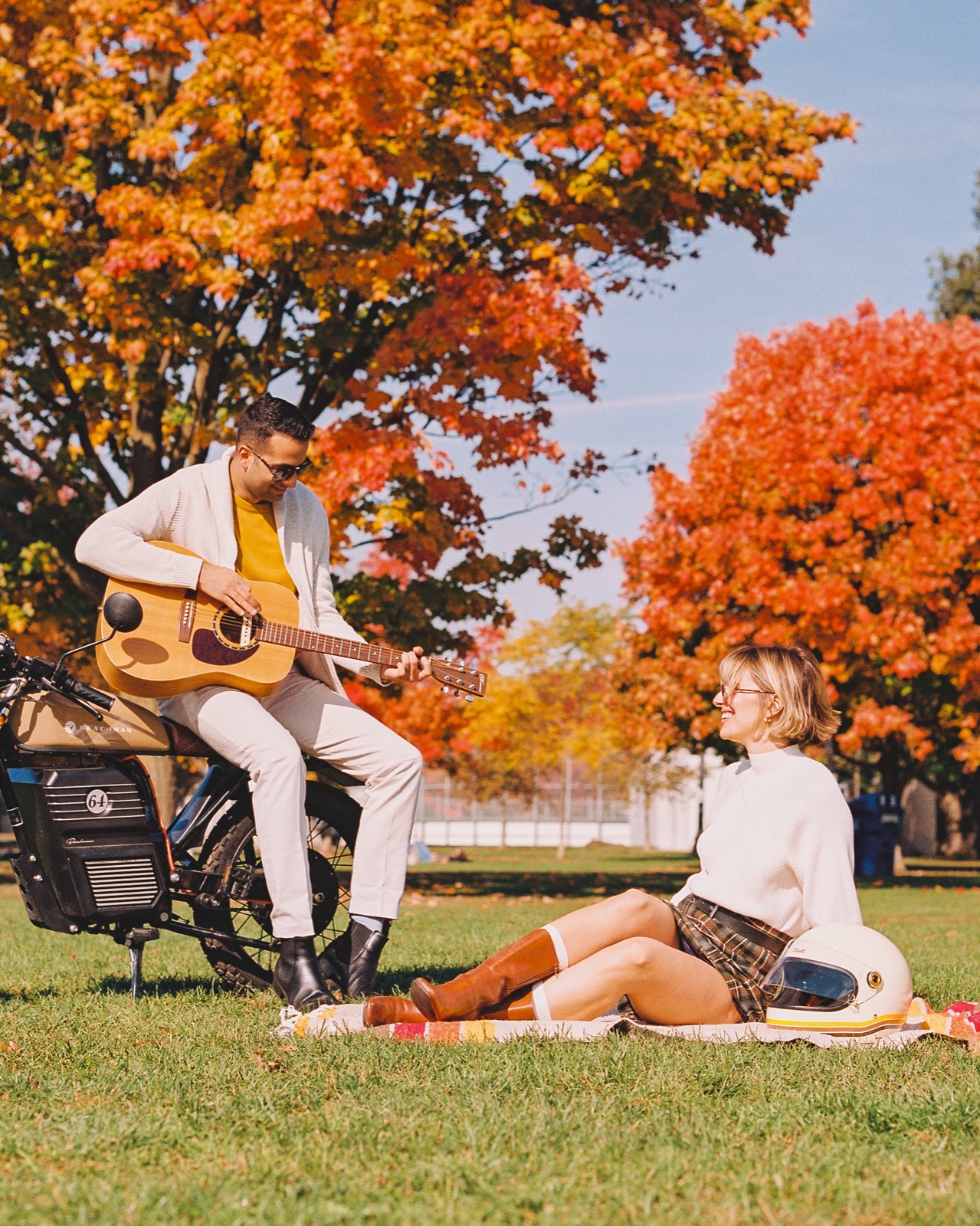 A couple beside an electric motorbike under blazing autumn trees, shot on warm film