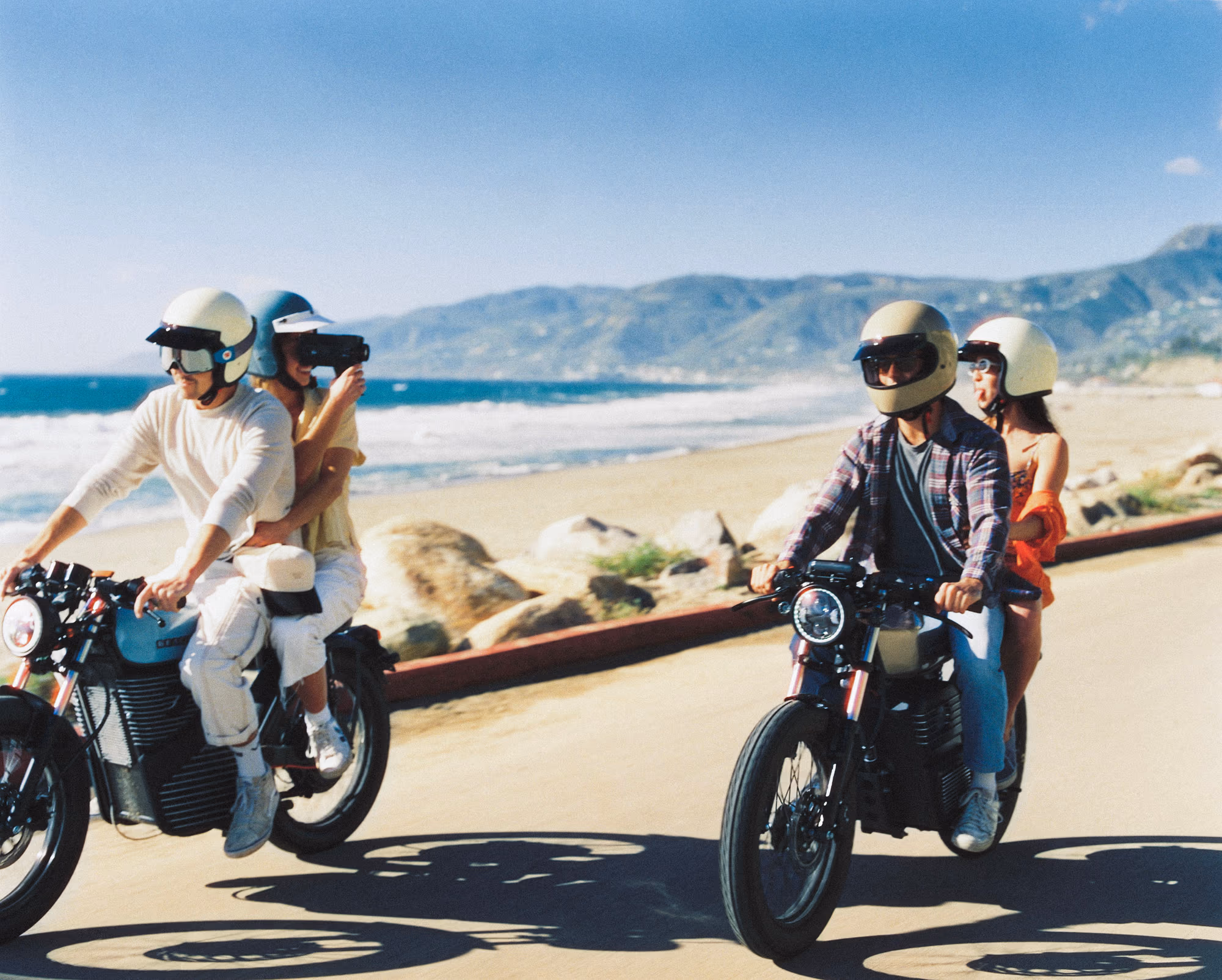 Two Beachman bikes cruising a coastal road, the Pacific behind them