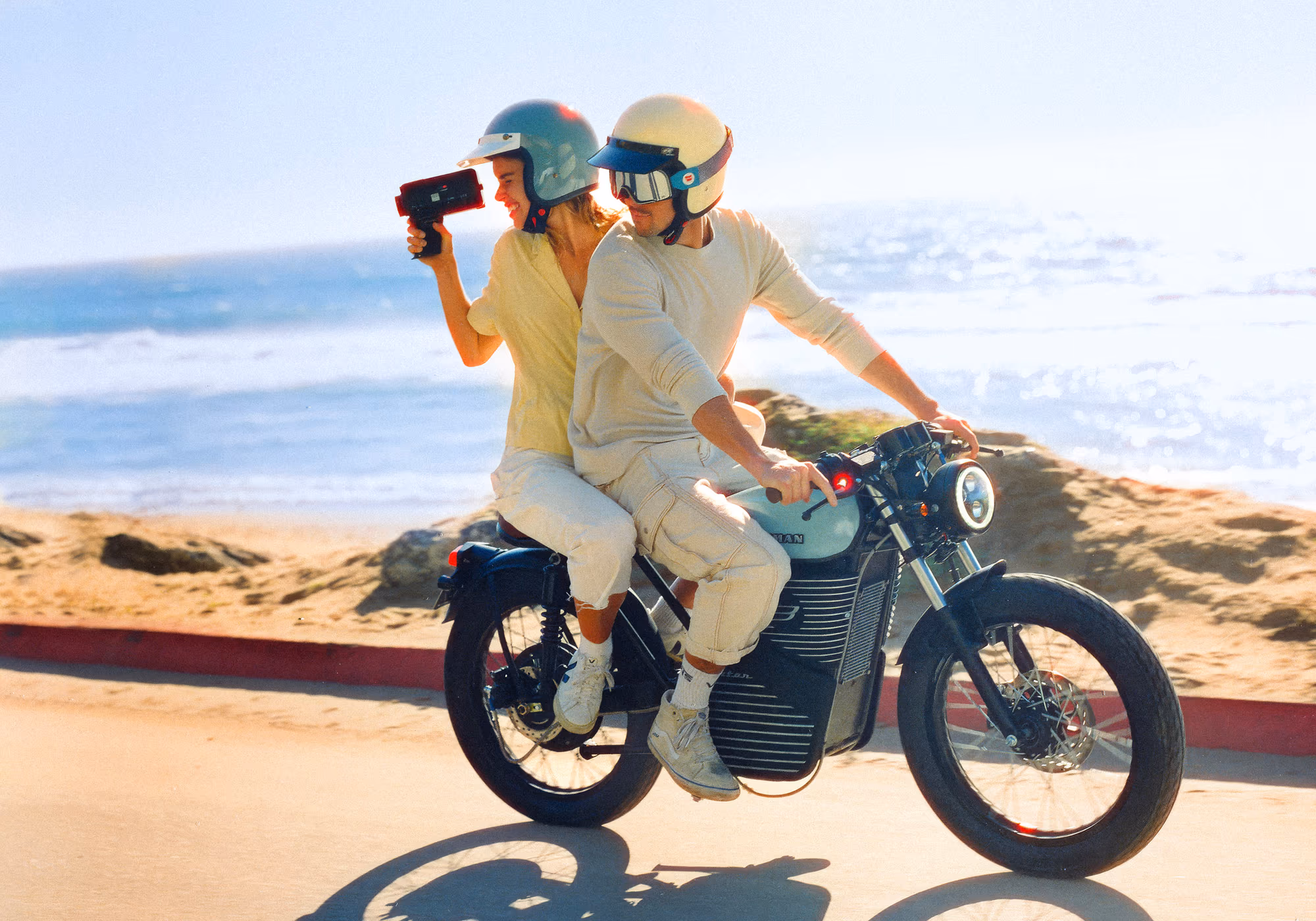 The passenger filming from the back of a parked bike at the beach