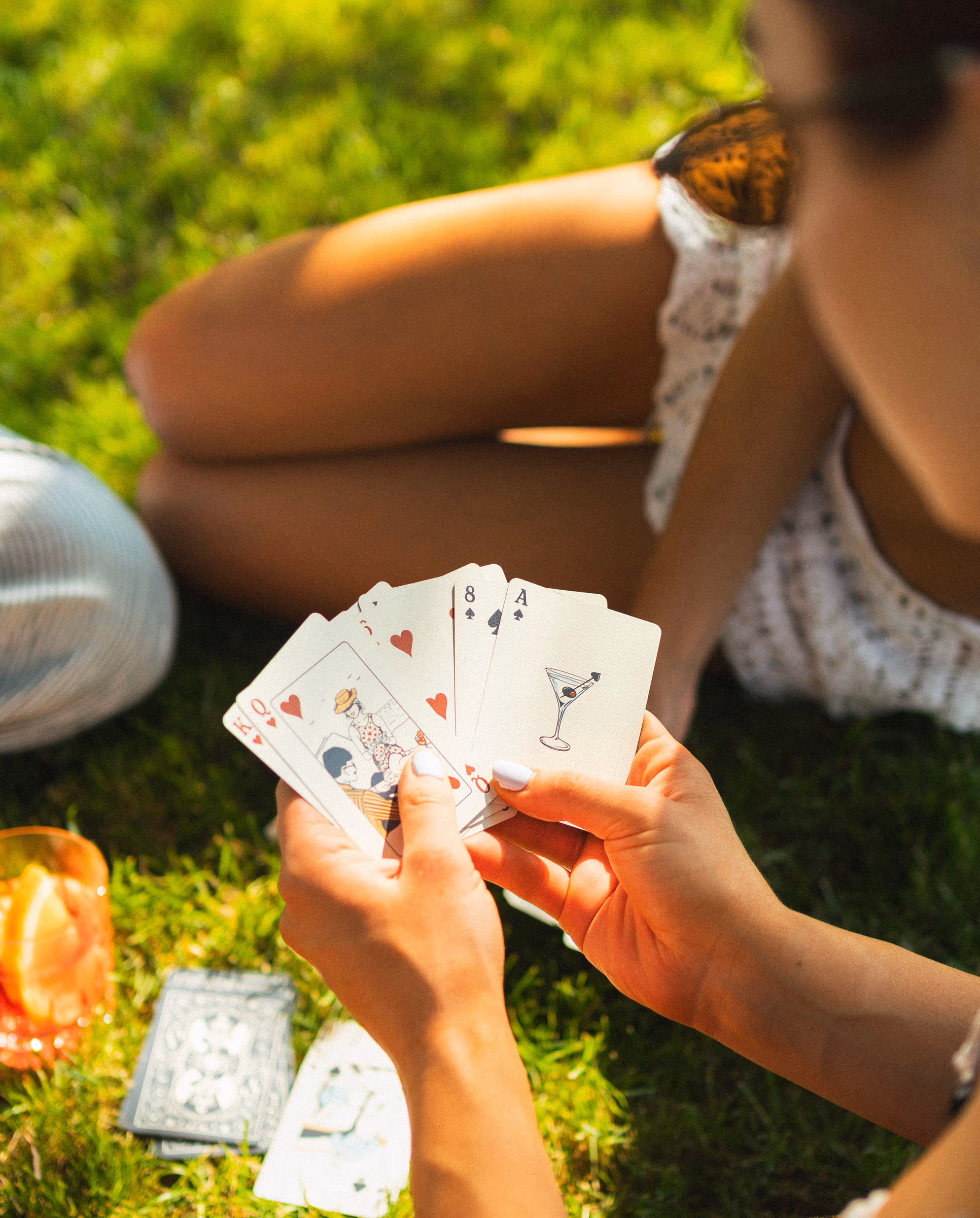 A fanned hand and a drink at the wooden table, Beachman deck in play