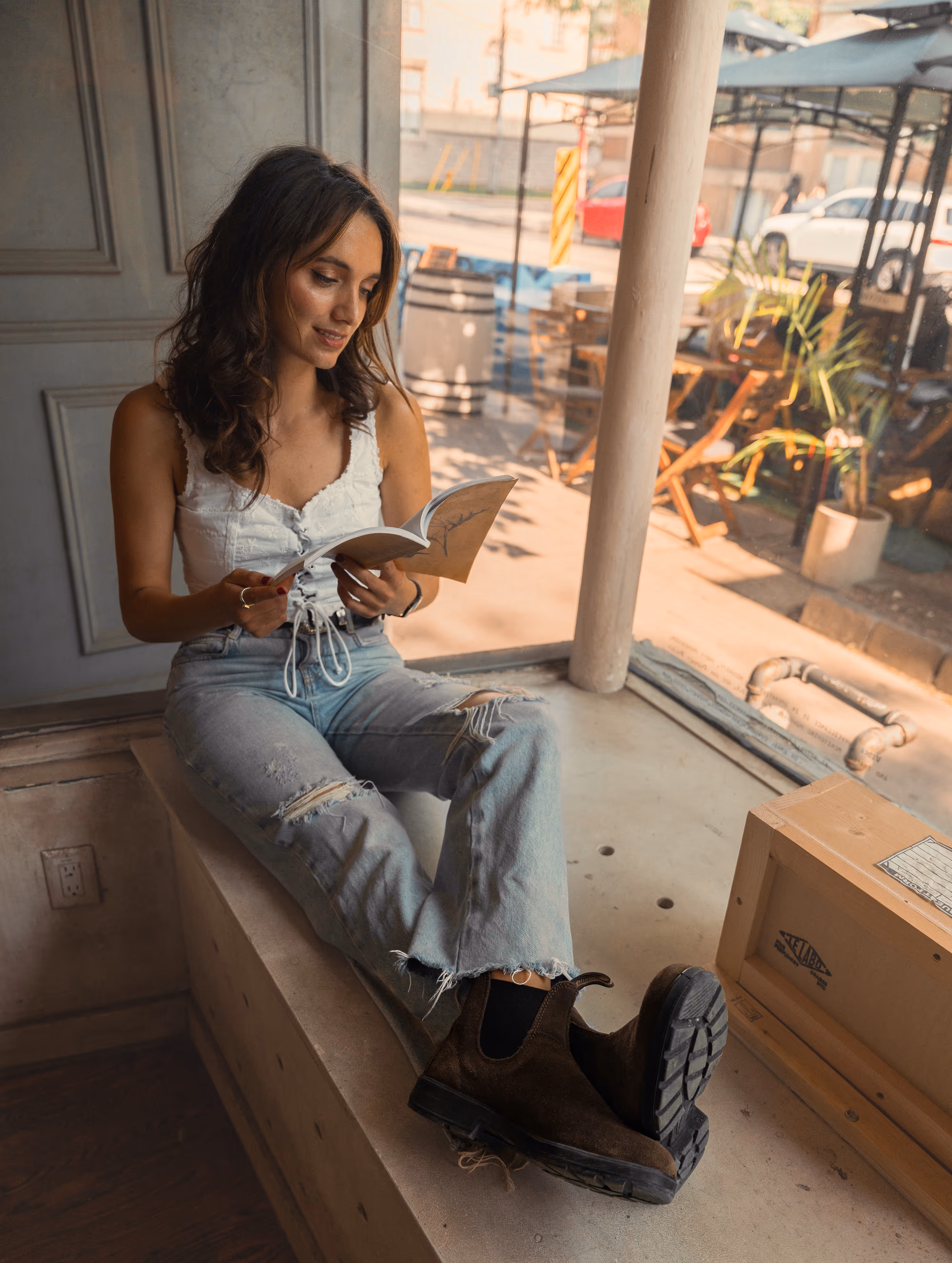 Reading in a café window seat, Blundstones kicked up on the ledge