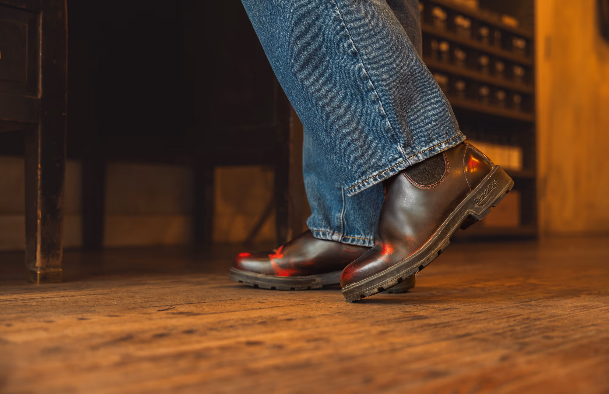 Polished dark-cherry boots on hardwood, warm indoor light