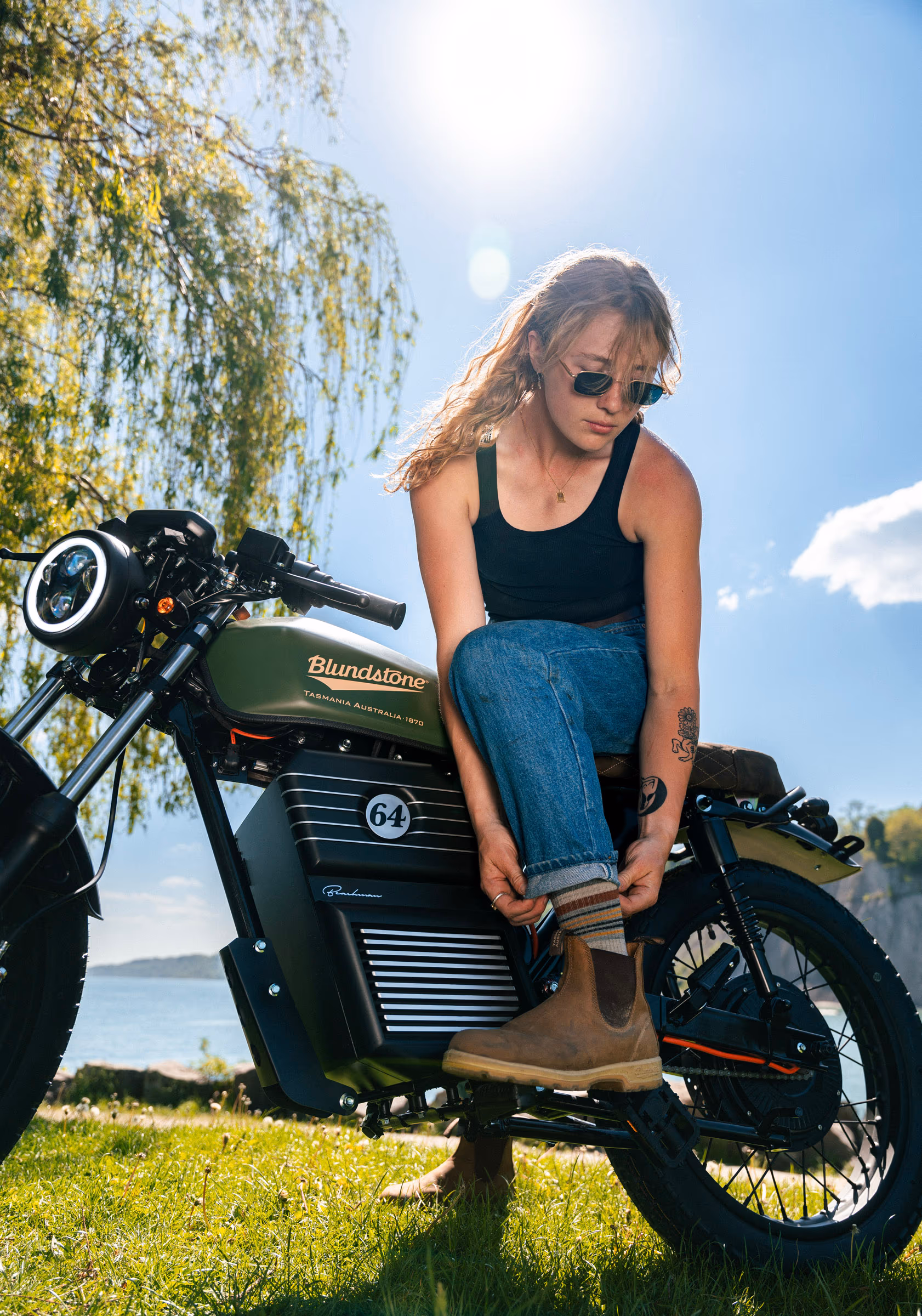 A rider pulling on Blundstone boots while seated on the bike