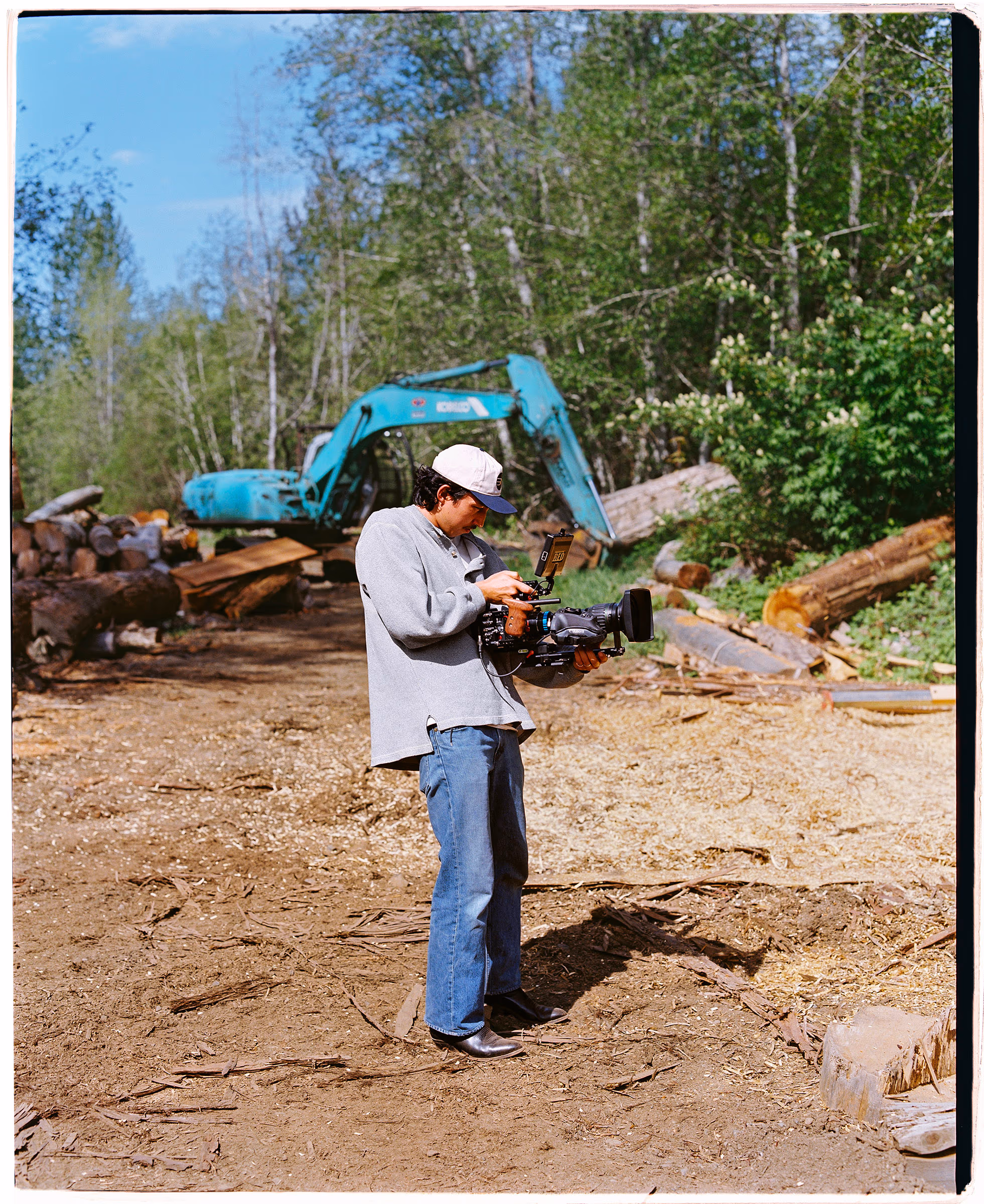 The excavator swinging logs at the edge of the clearing