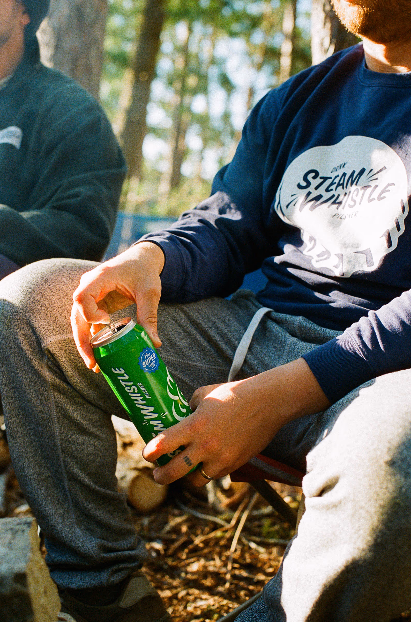 Cracking a can in a Steam Whistle crewneck at the campsite