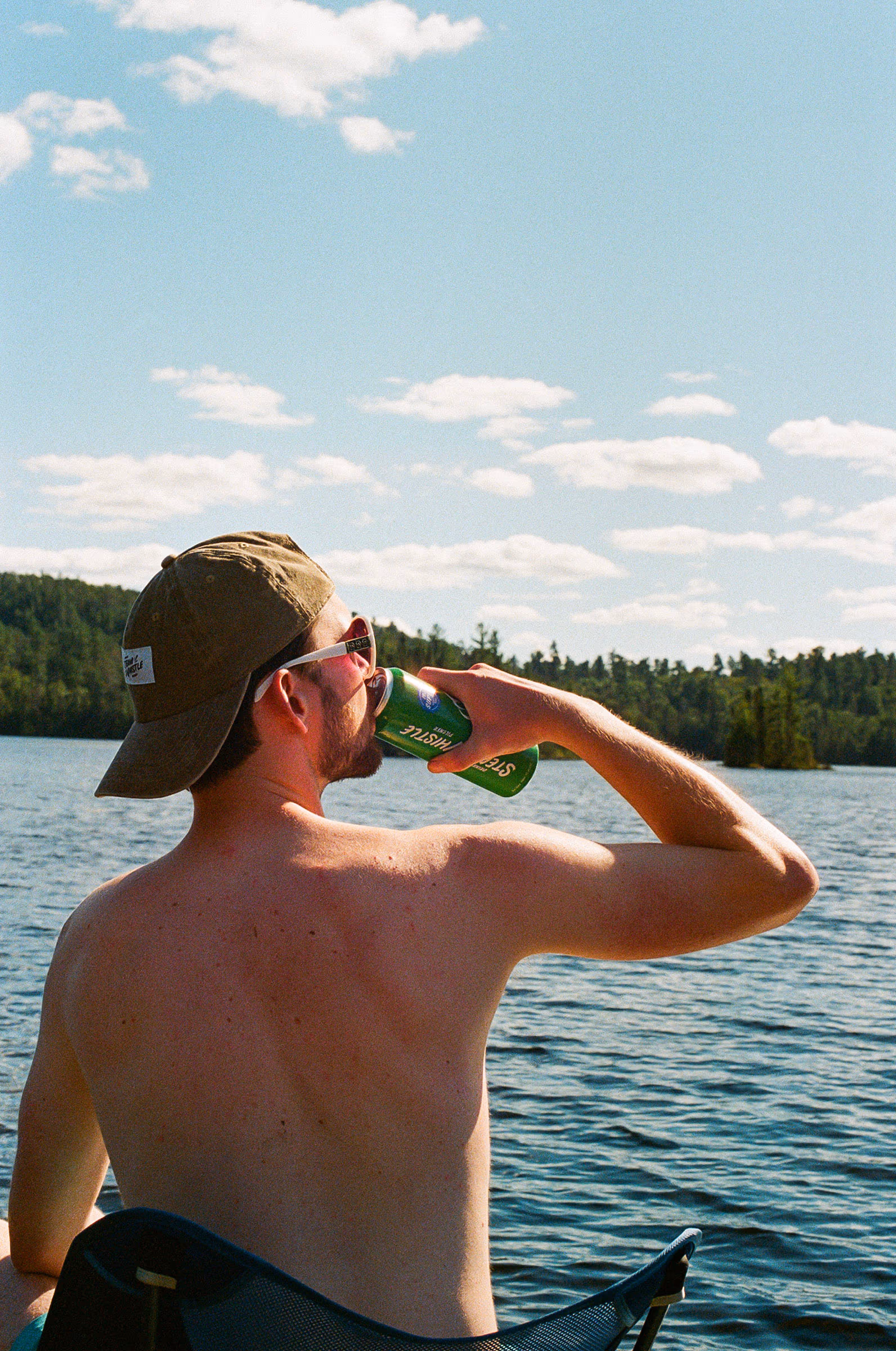 A long drink facing the open lake in a bucket hat