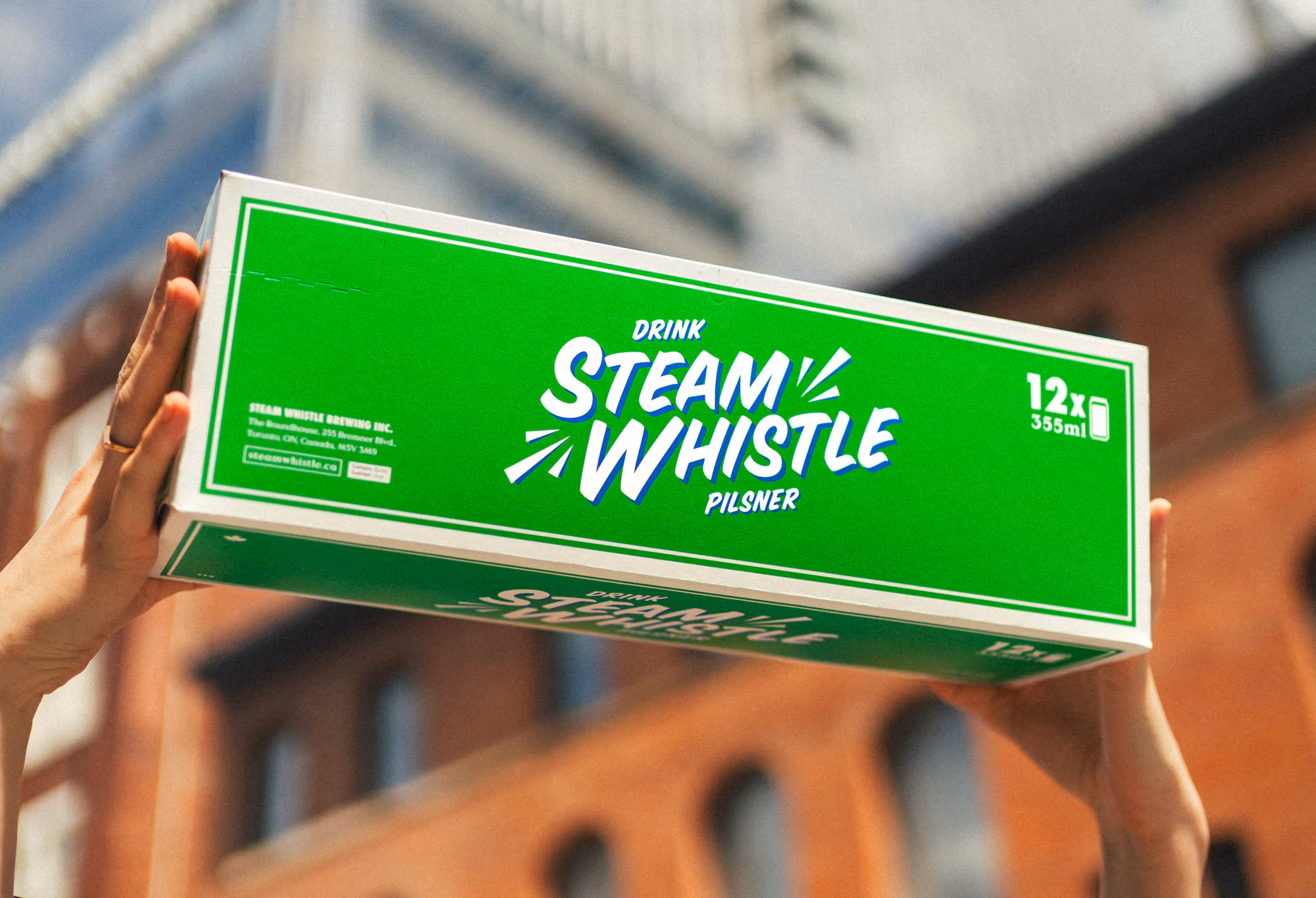 The green 12-pack held up against the brick warehouses