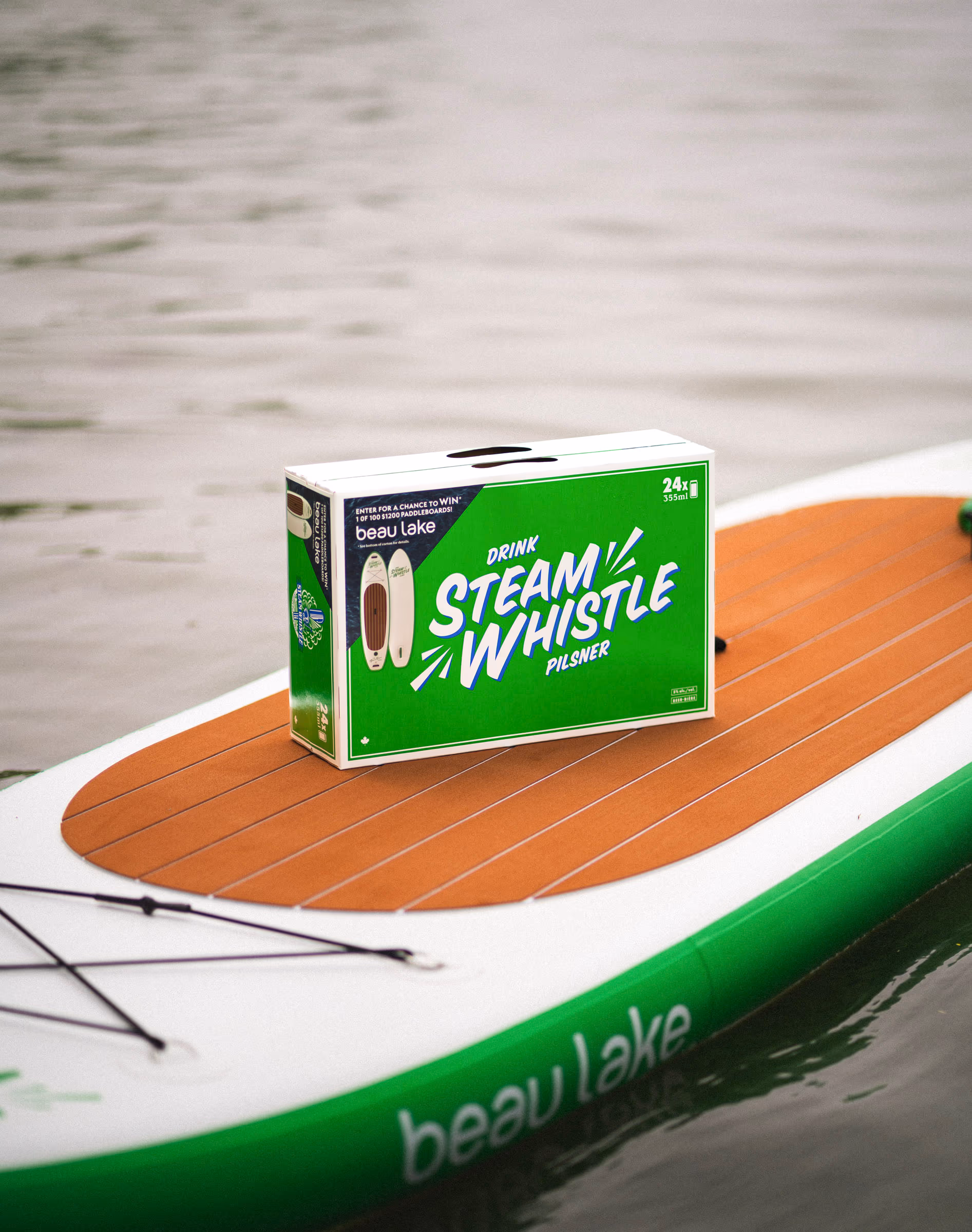 A Steam Whistle case riding a co-branded Beau Lake paddleboard on the water