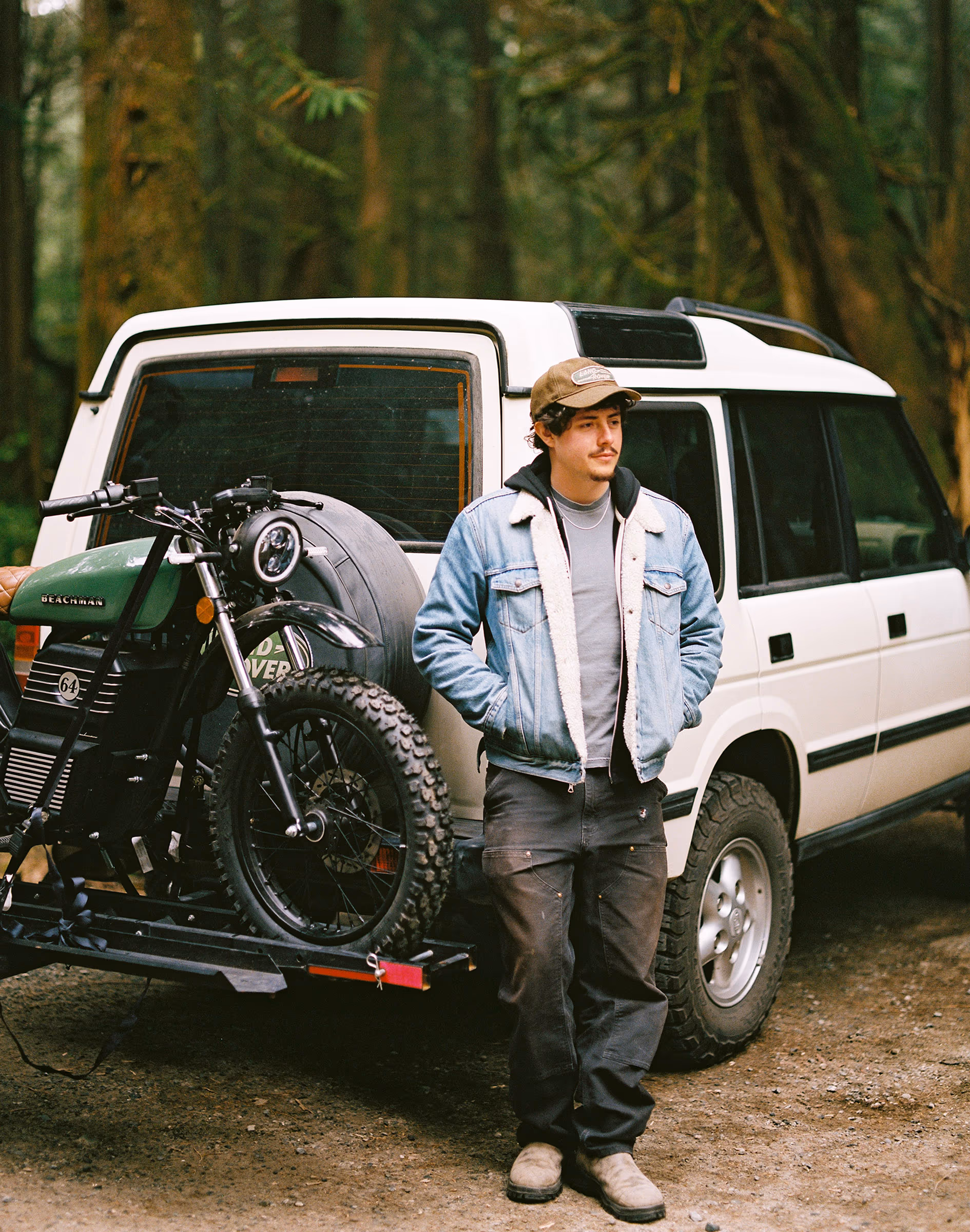 Yair Martinez with his camera beside a 4x4 loaded with a motorbike