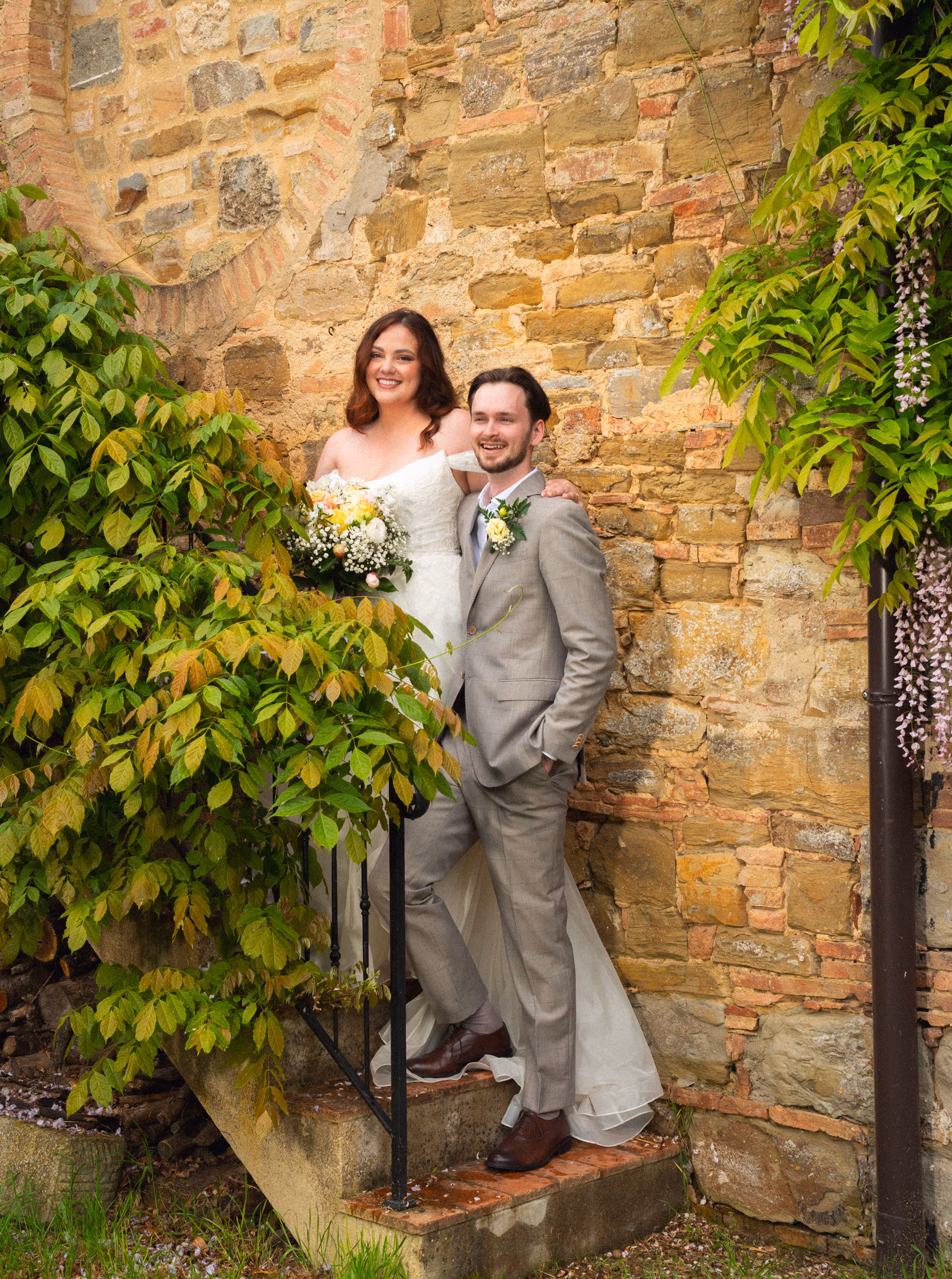 The couple on the old stone steps beneath the vines