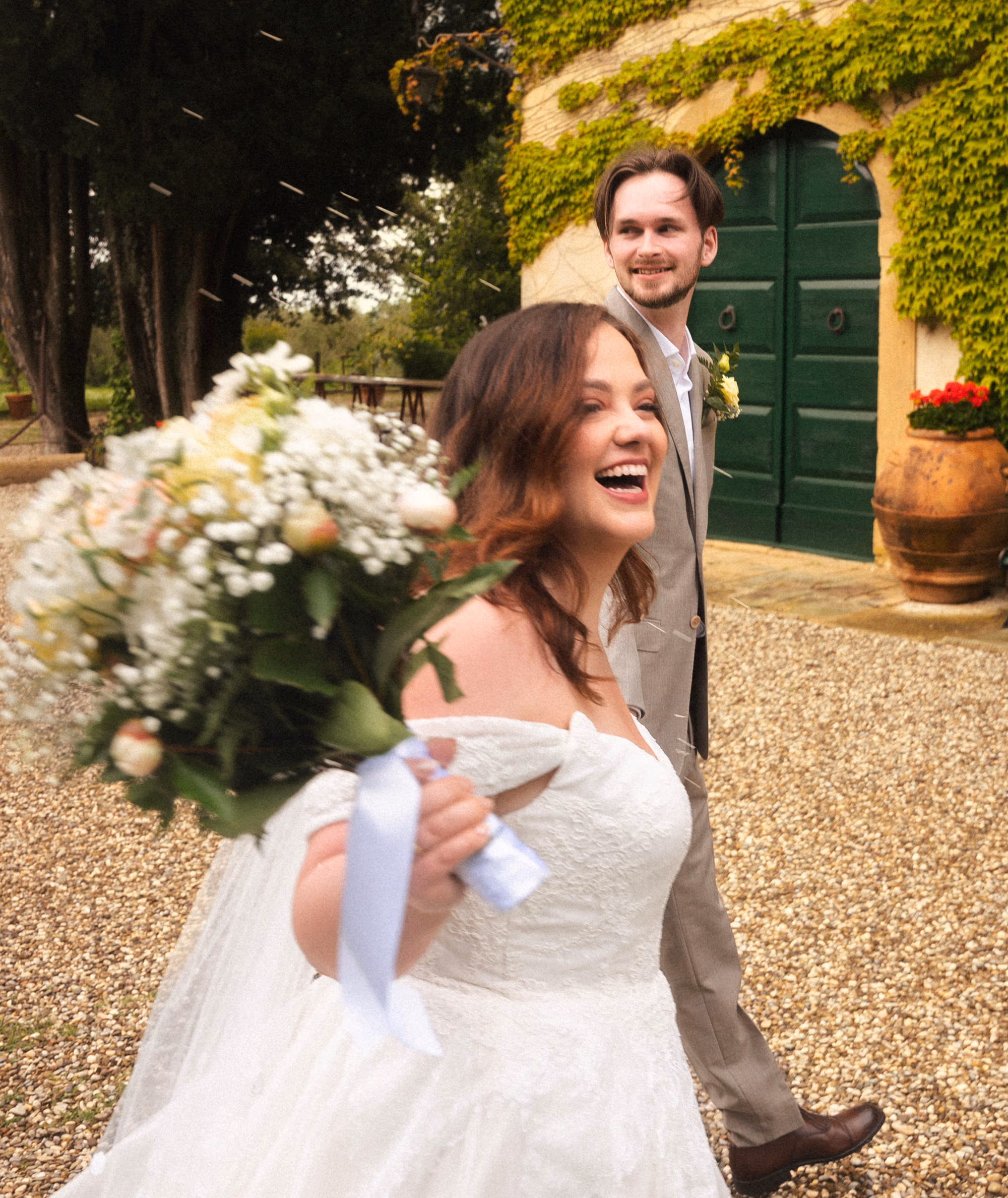 The bride laughing in the courtyard, bouquet still in hand
