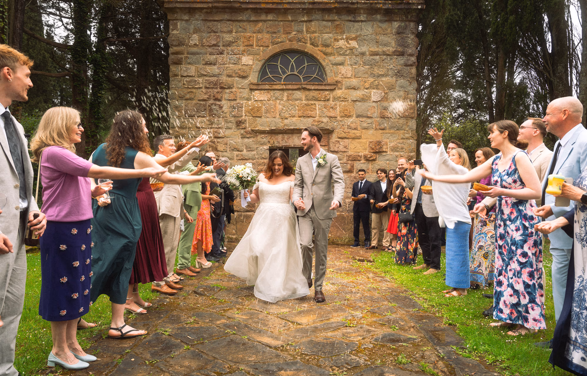 A couple walking out through a confetti toss from family and friends after their wedding