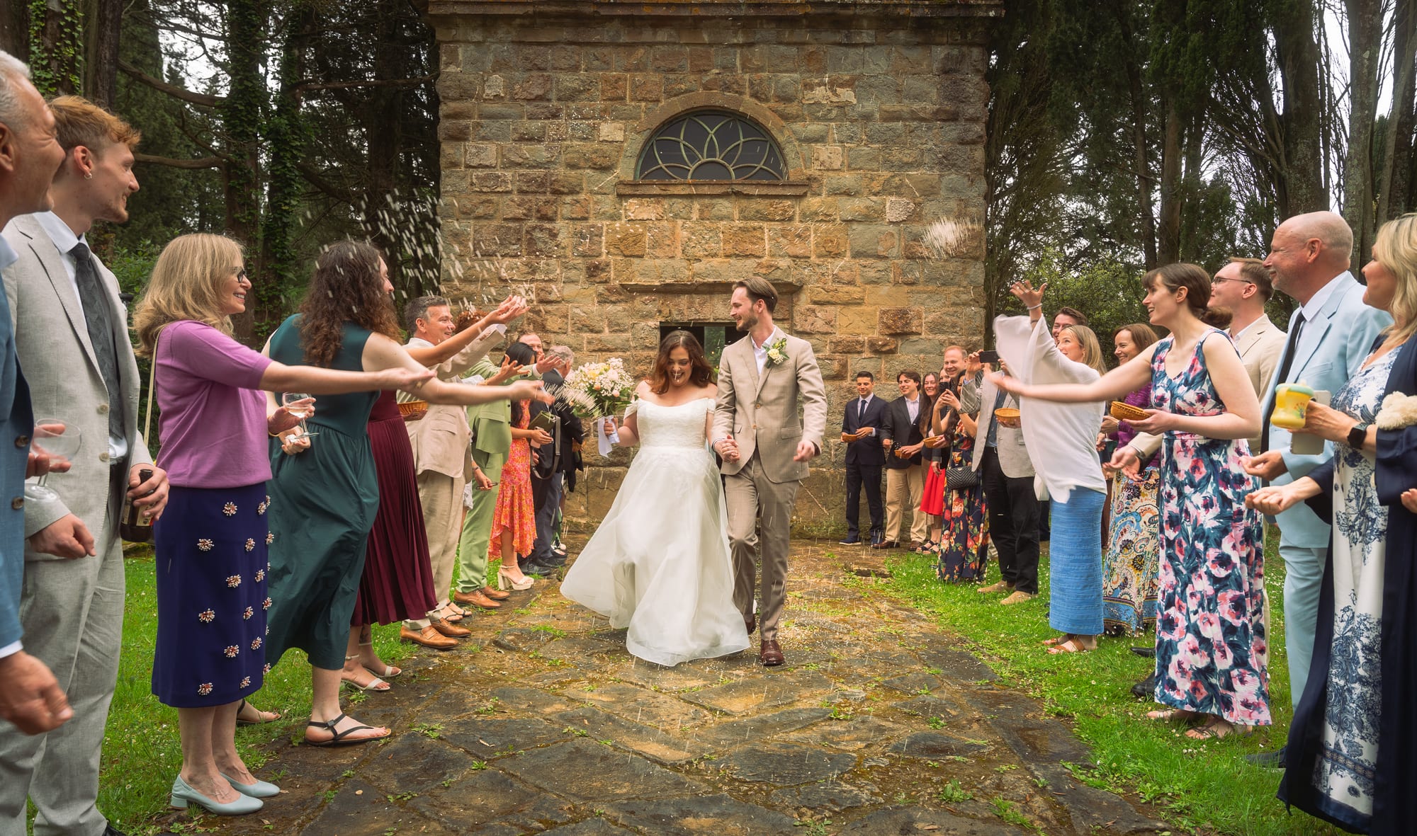 A couple walking out through a confetti toss from family and friends after their wedding