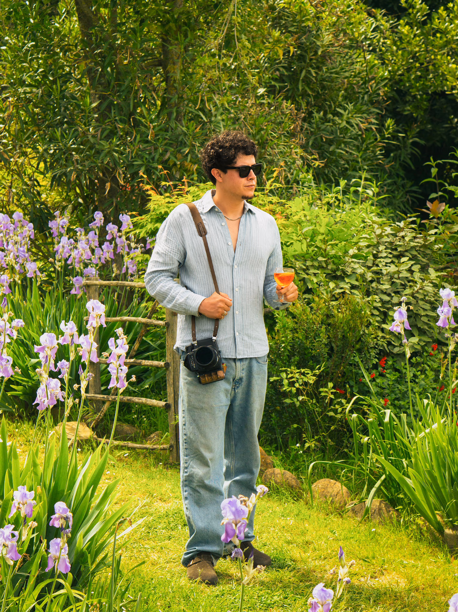 Yair Martinez with his camera in a garden of irises, holding a glass of wine